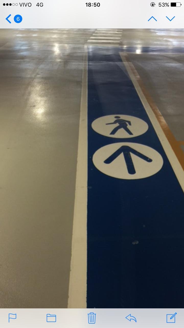 Piso epóxi industrial aplicado em estacionamento com faixa azul de circulação